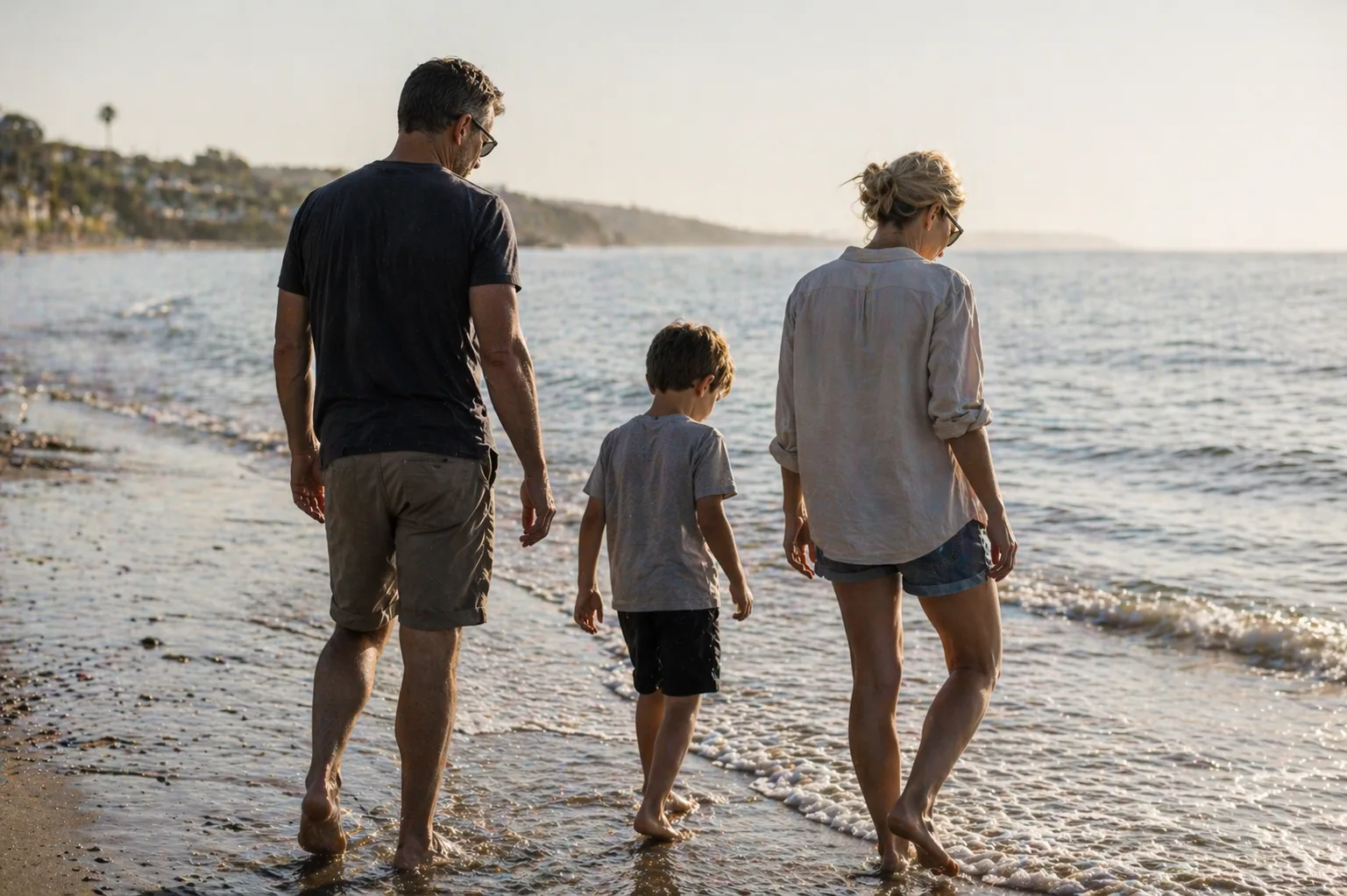 Family walking together along the shoreline at golden hour