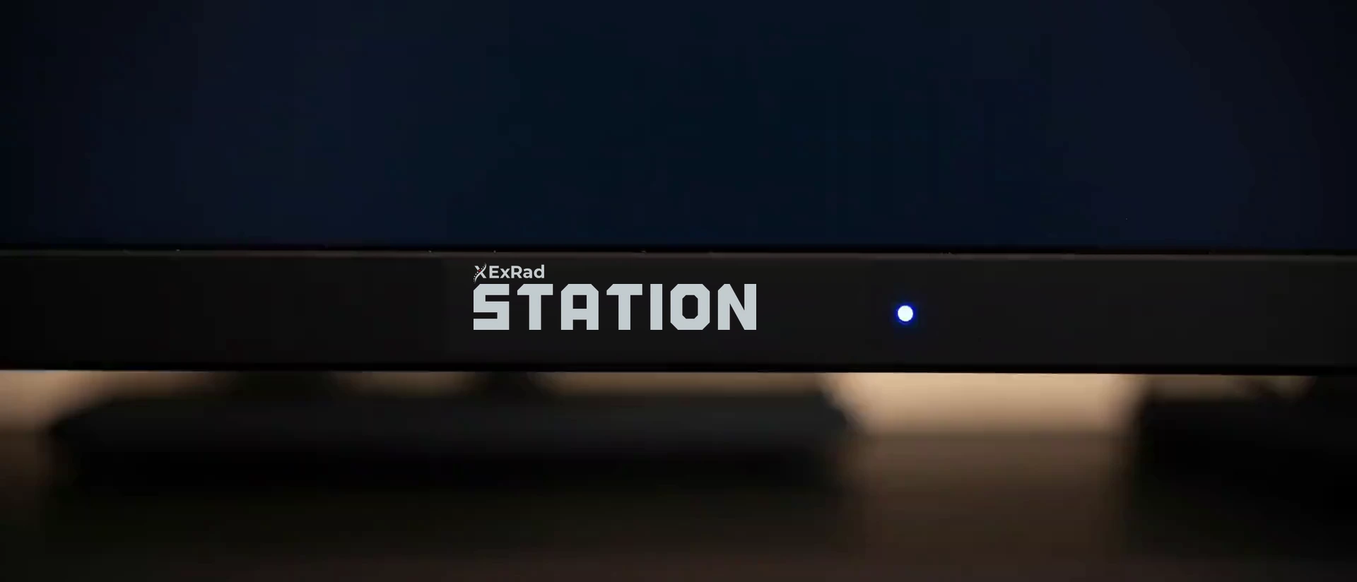 A close cinematic view across the lower bezel and stand of the workstation displays